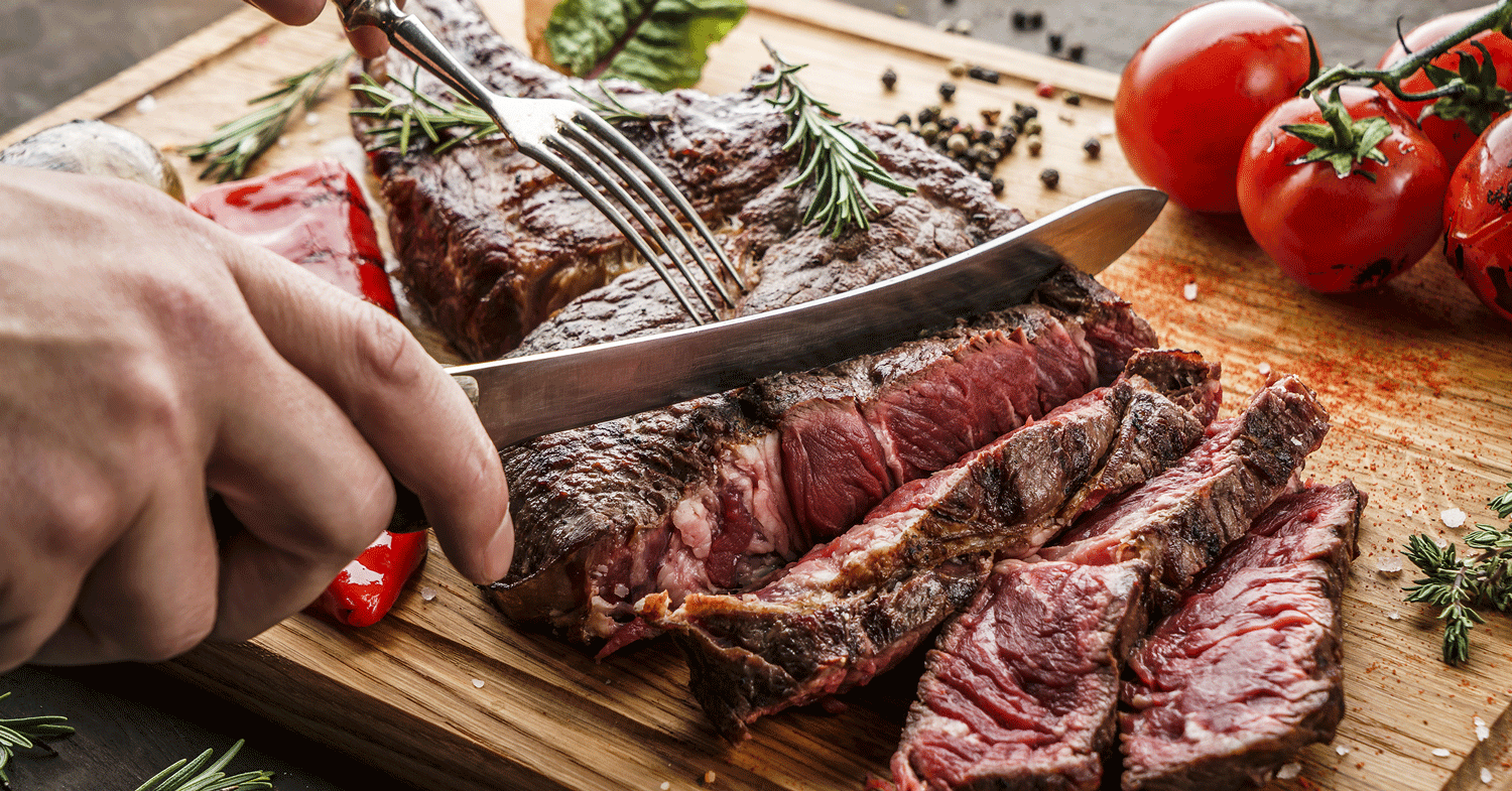 Vitamin-B12 Saftiges Stück Fleisch wird auf einem Brett geschnitten
