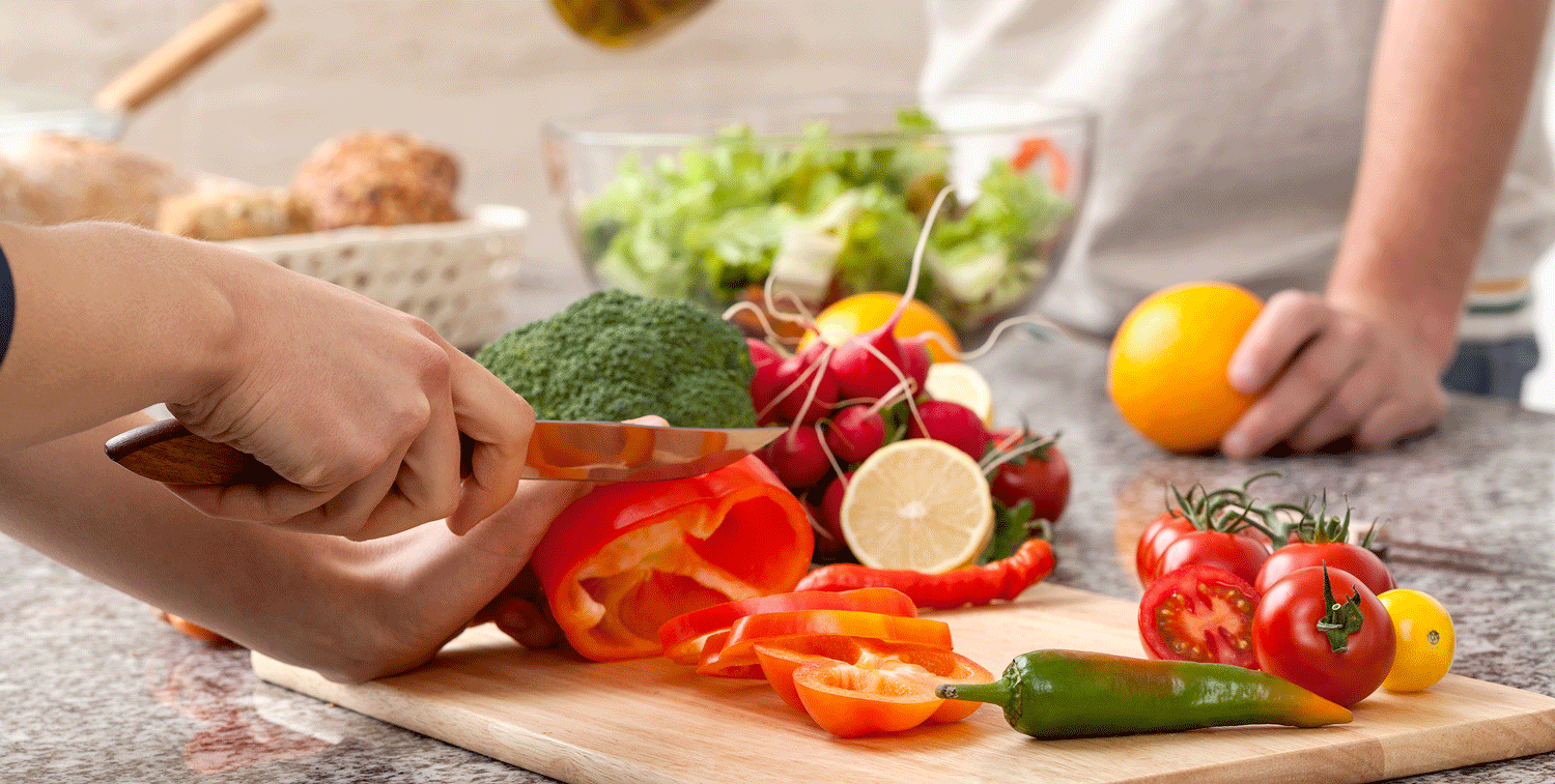 Vitamine Frisches Gemüse wird auf einem Brett geschnitten