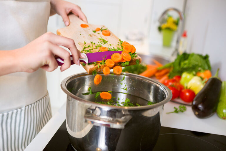 Vitamin A haltige Karotten werden in eine Suppe getan.
