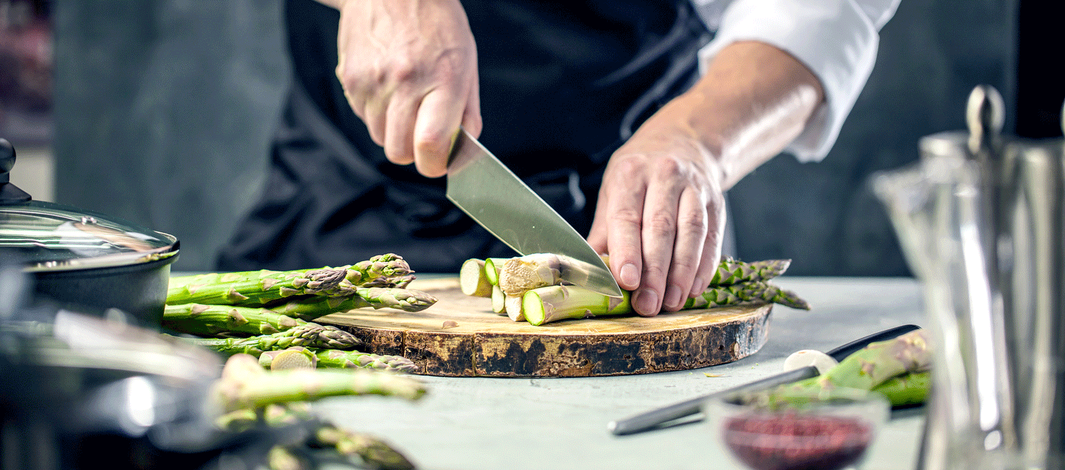 Selenmangel Koch schneidet Spargel auf einem Brett